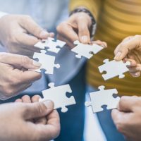 A group of business people assembling jigsaw puzzle. The concept of cooperation, teamwork, help and support in business.